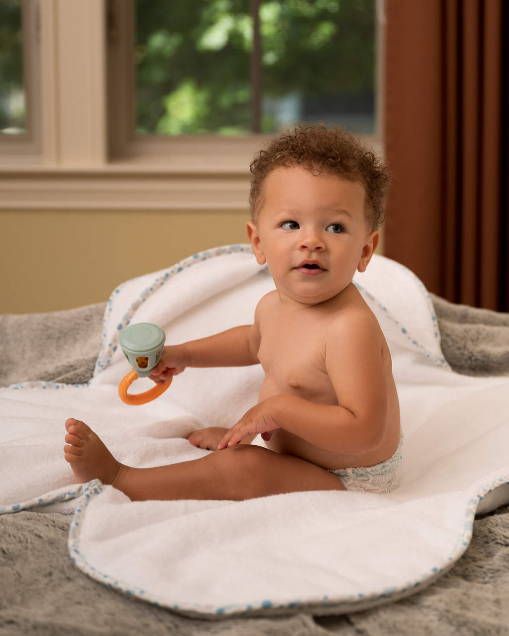 Baby on white EleryB towel with blue geometric trim, full view
