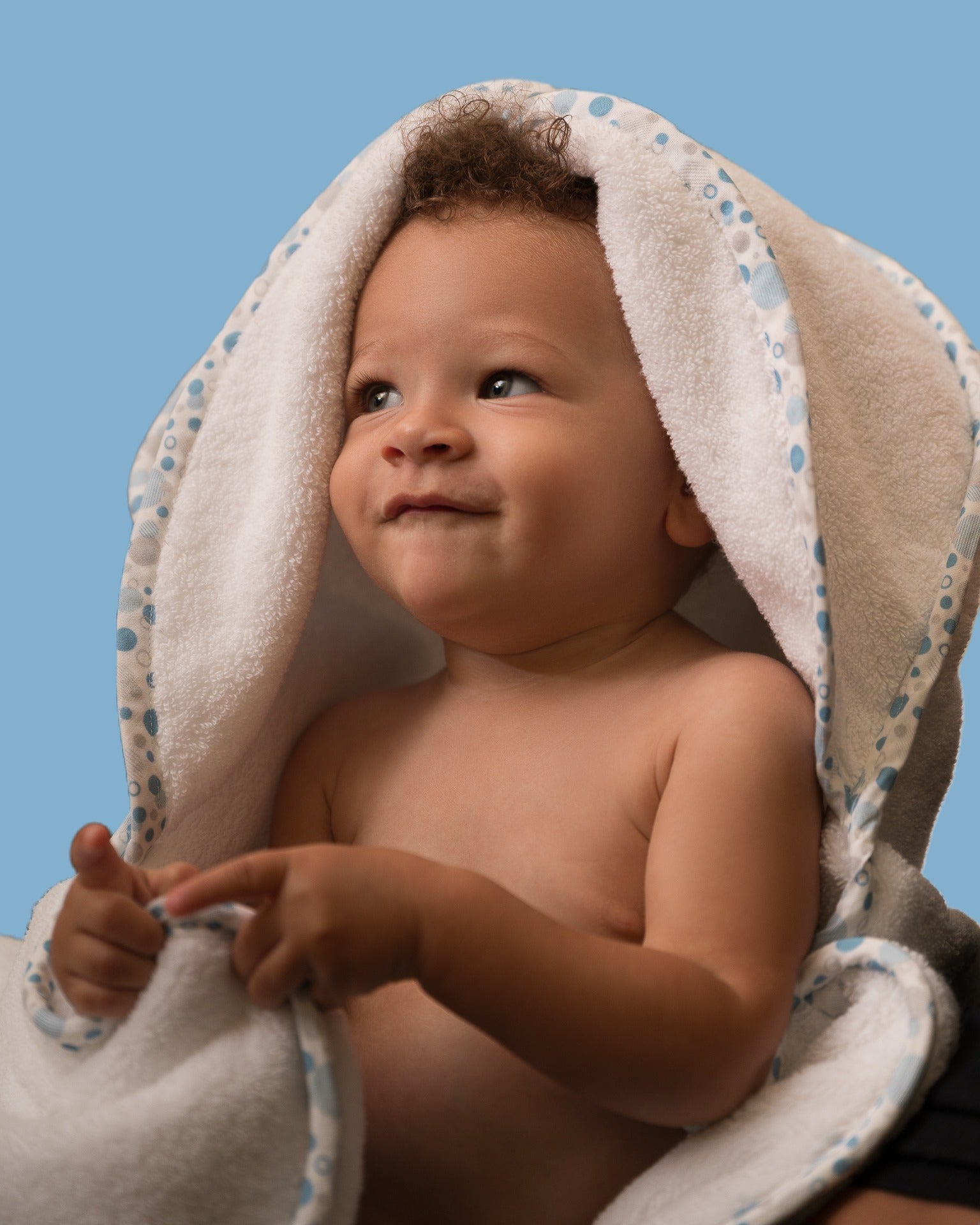 Toddler in EleryB hooded towel with blue geometric trim and lamb logo with folded back head flaps
