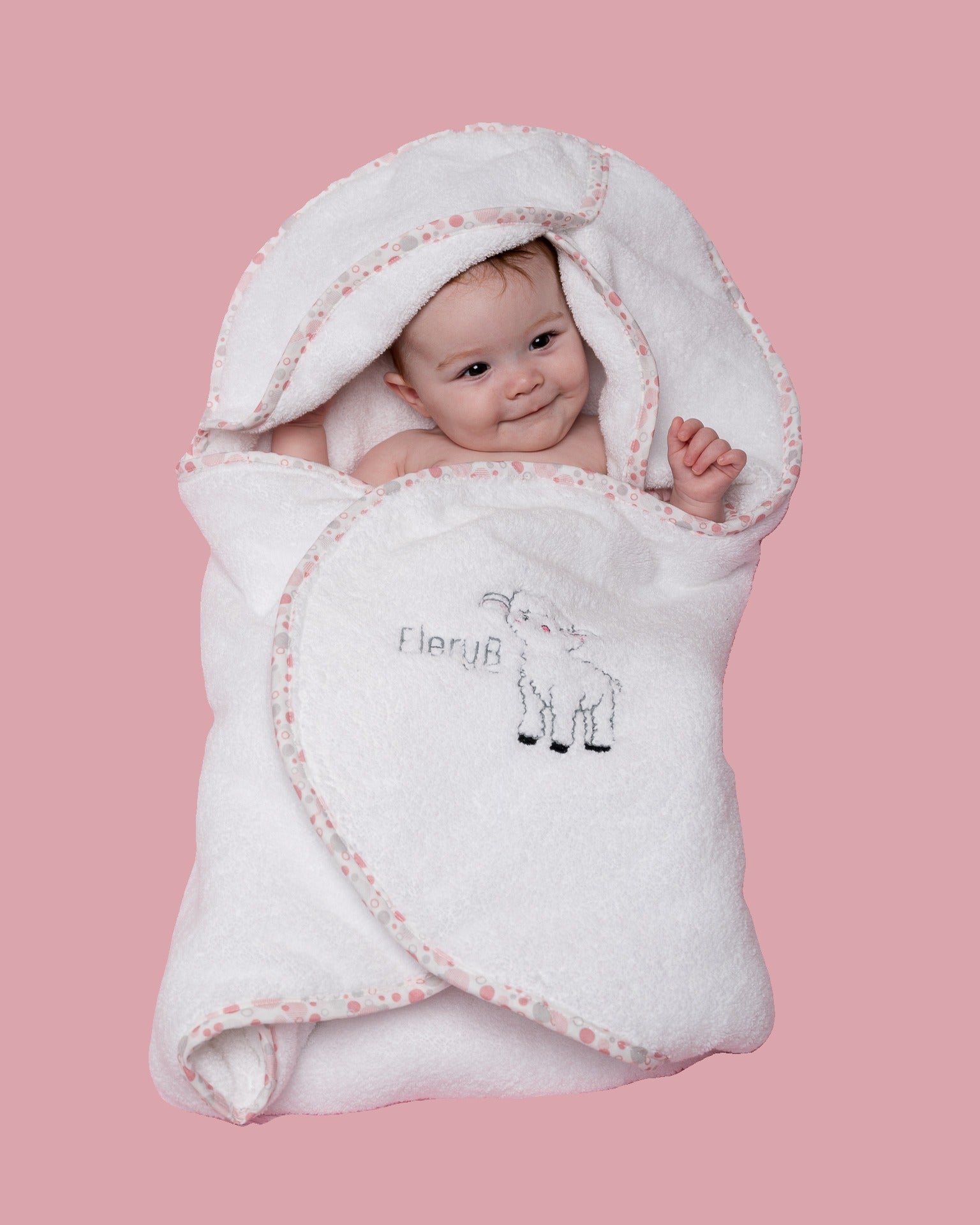 Infant swaddled in white EleryB hooded towel with pink geometric trim
