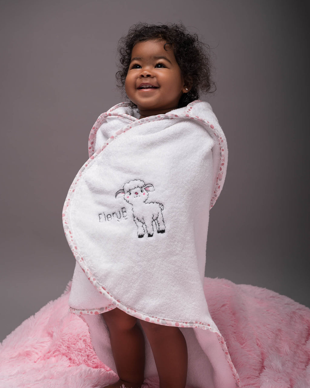 Toddler standing up in EleryB hooded towel with pink geometric trim and lamb logo
