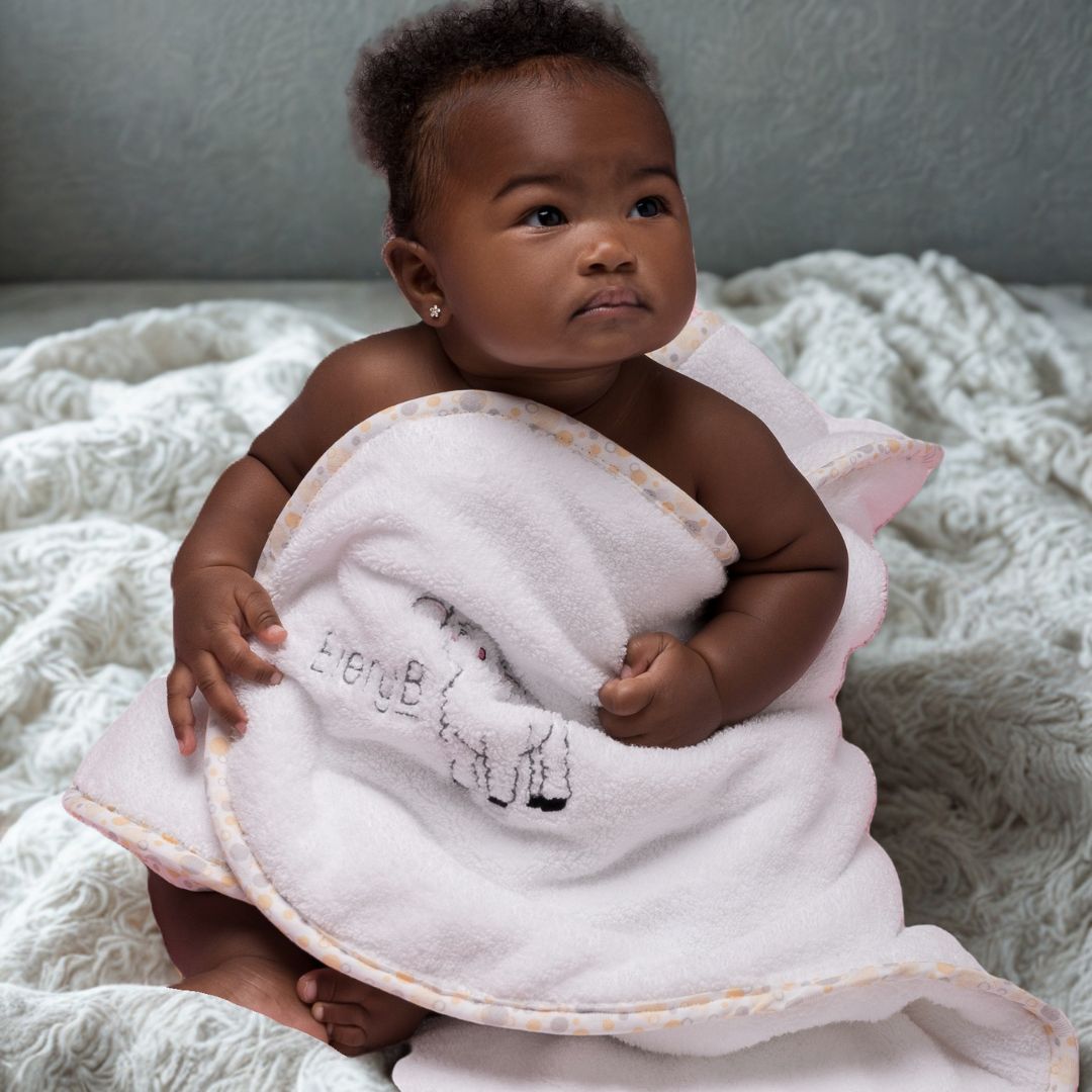 Seated baby wrapped in hypoallergenic EleryB towel with yellow geometric trim and soft texture
