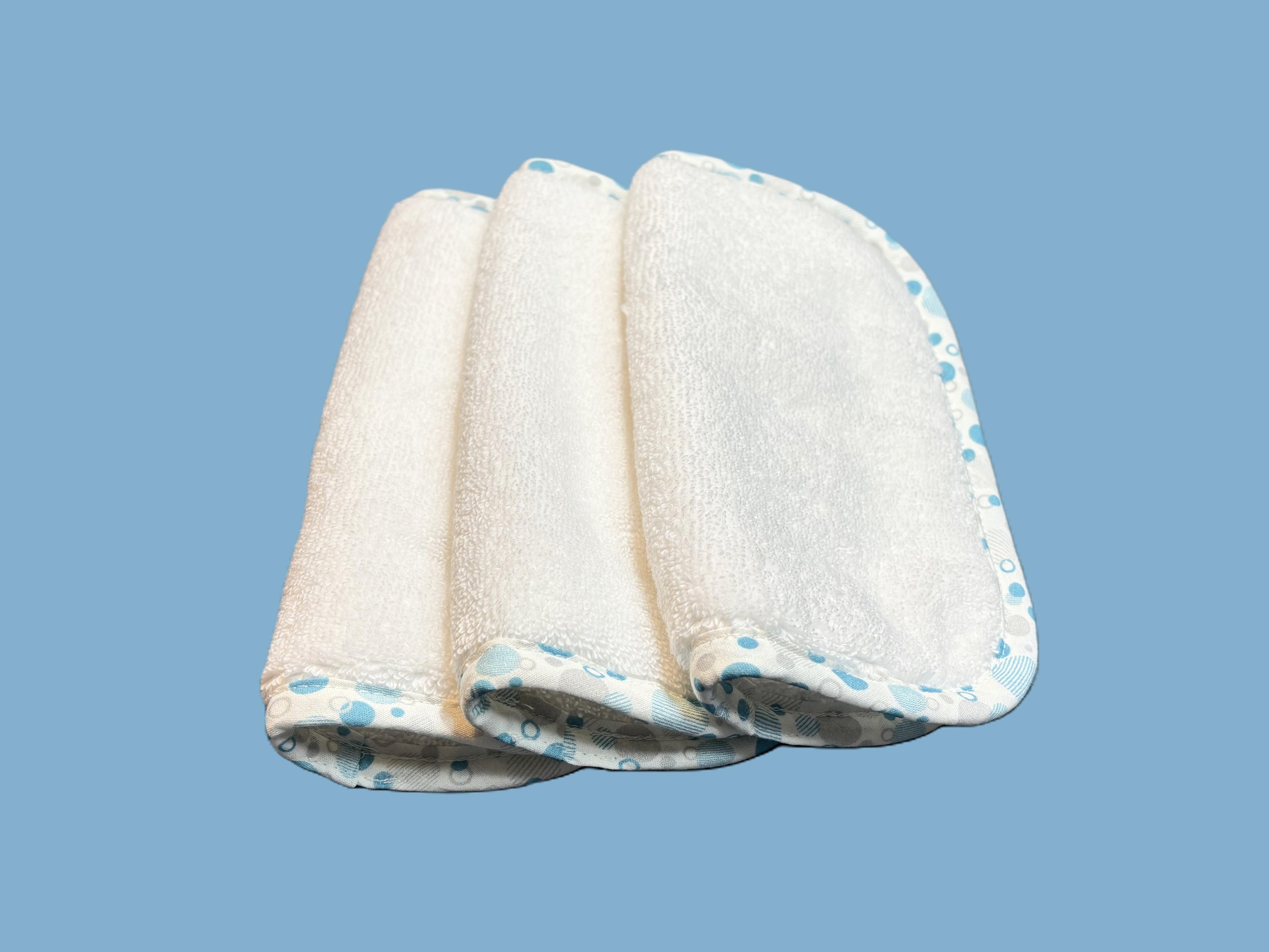 Three ultra-soft EleryB washcloths with blue geometric trim, folded and stacked
