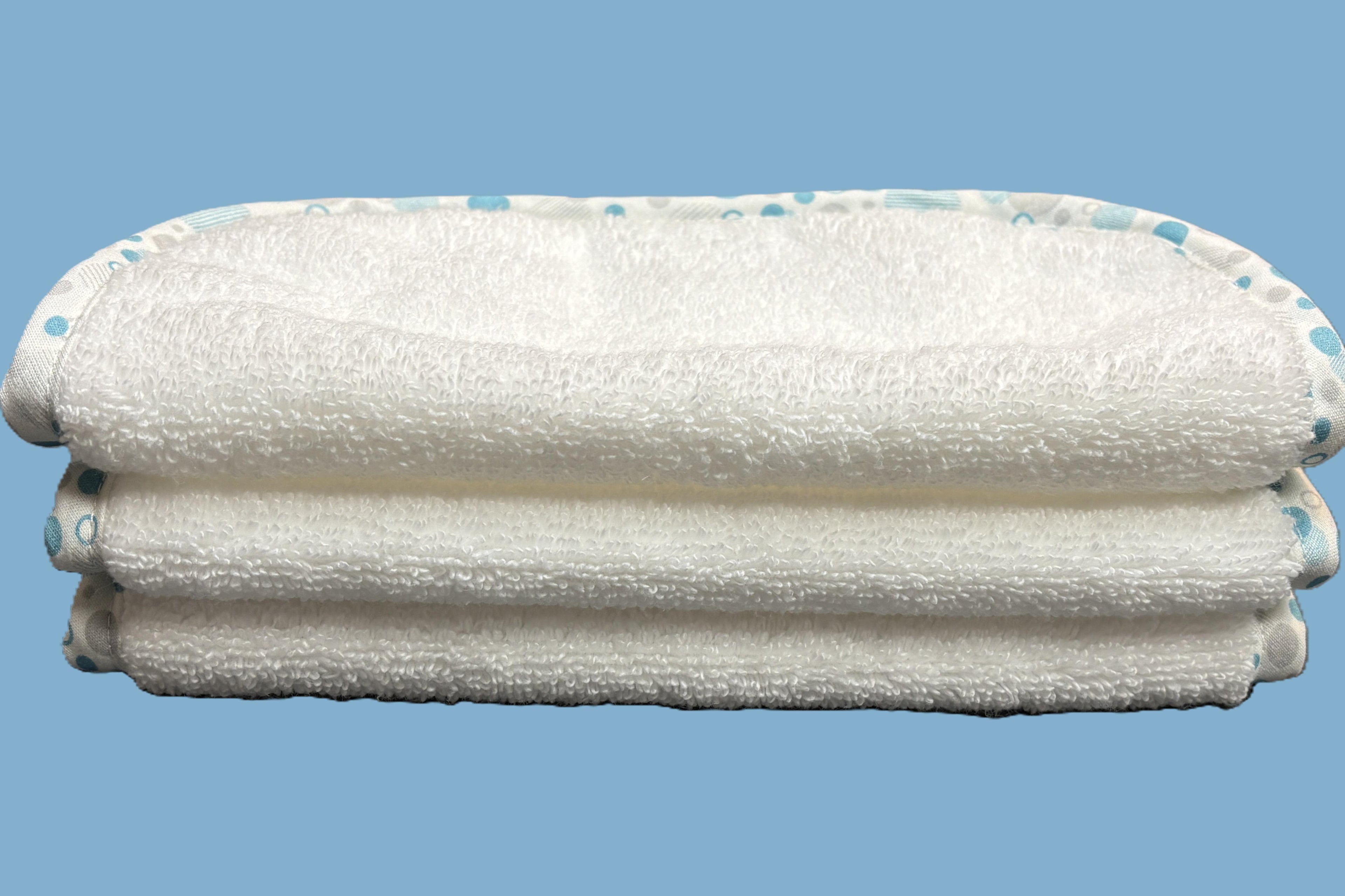 Three stacked white EleryB hypoallergenic washcloths with blue geometric trim, folded in half
