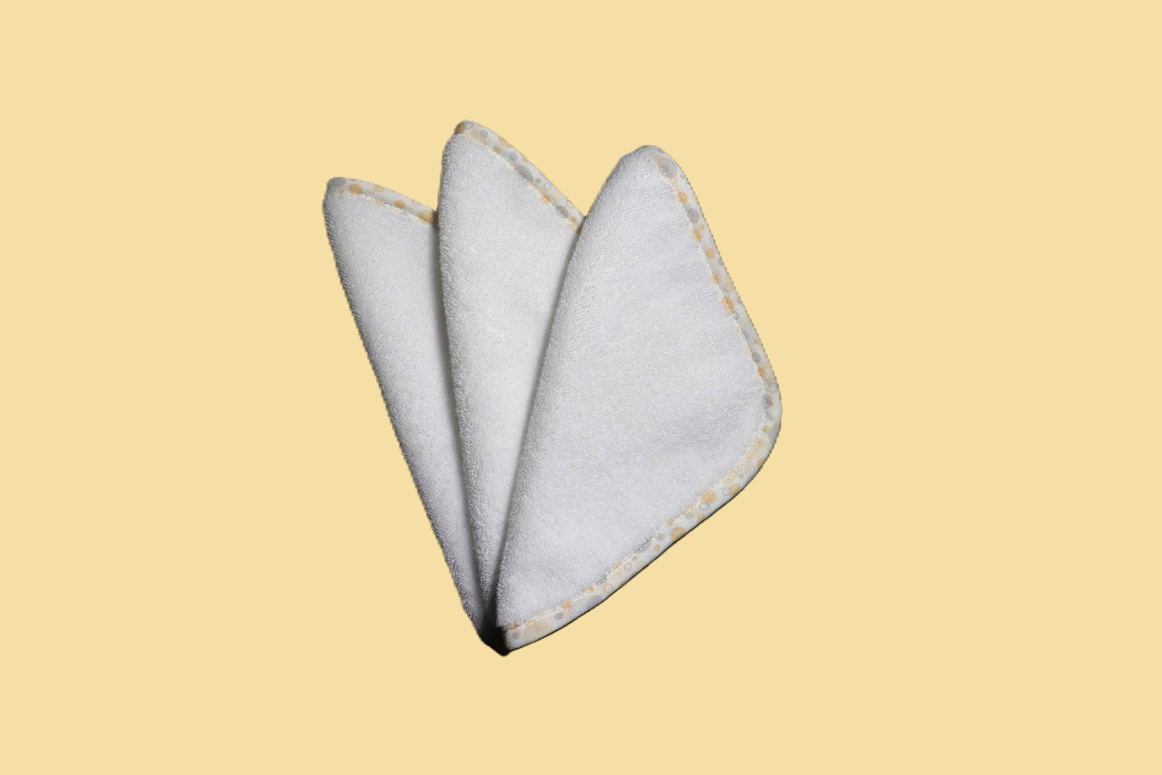 Three EleryB hypoallergenic washcloths with yellow geometric trim, triangle fold
