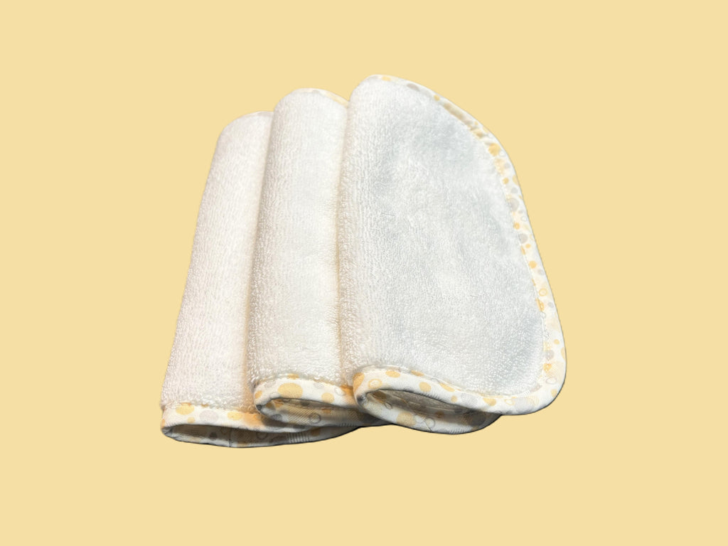 Three ultra-soft EleryB washcloths with yellow geometric trim, folded and stacked

