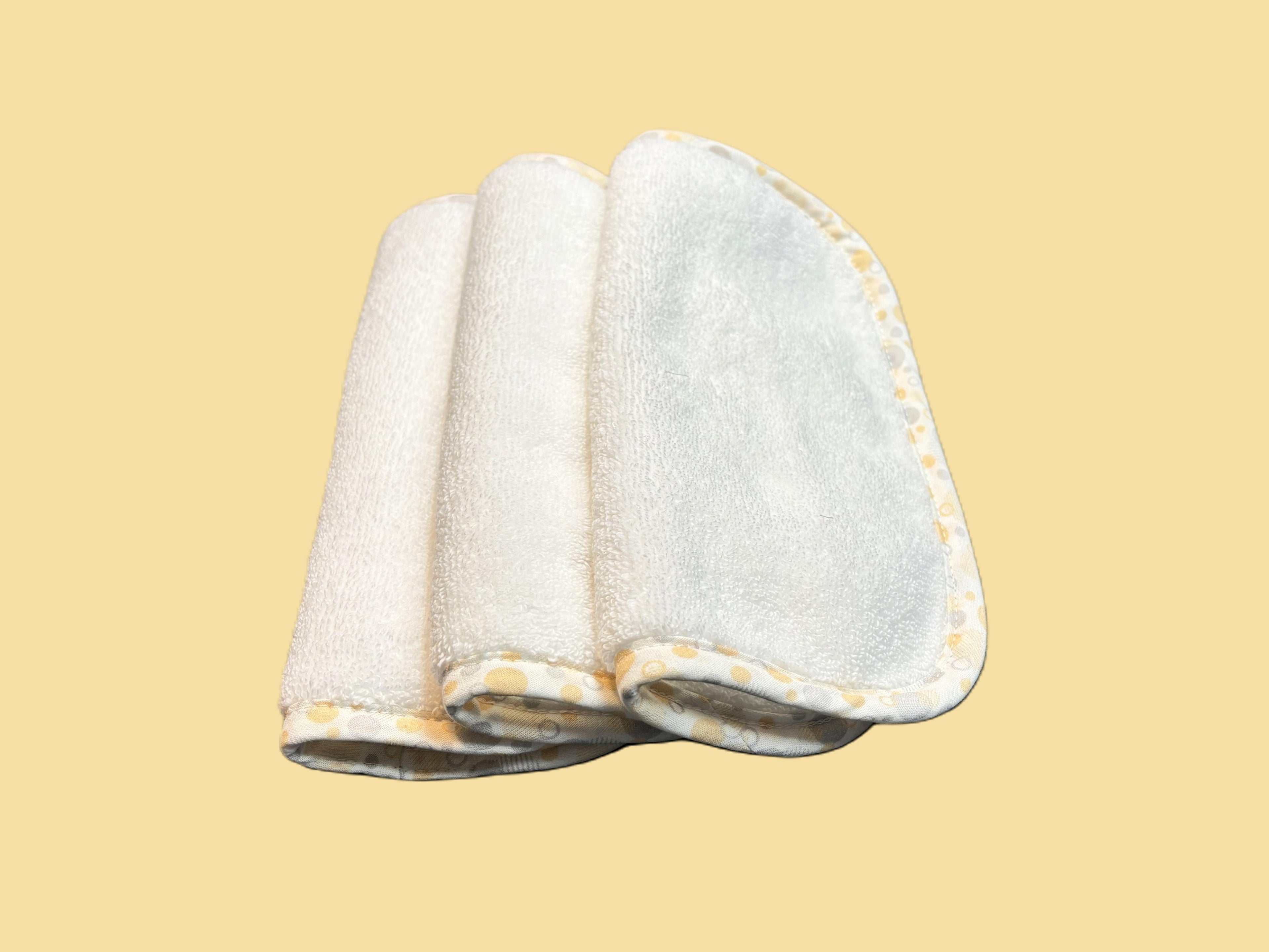 Three ultra-soft EleryB washcloths with yellow geometric trim, folded and stacked
